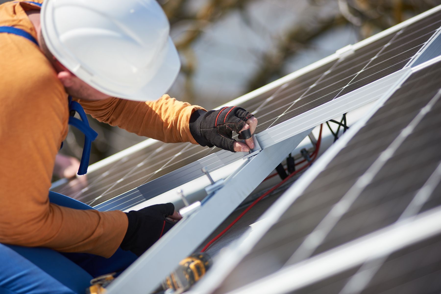 Männliche Arbeiter bei der Installation eines photovoltaischen Solarsystems. Elektriker bei der Montage eines blauen Solarmoduls auf dem Dach eines modernen Hauses. Ökologisches Konzept für alternative Energien.